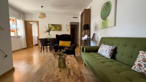 a living room with a green couch and a table at Apartamentos Alcazar de Baeza in Baeza
