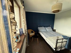 a bedroom with a bed and a blue wall at Domek nad jeziorem in Kikół