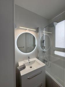 a white bathroom with a sink and a mirror at Apartment in the sky of Paris in Paris