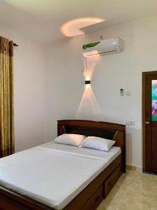 een slaapkamer met een bed met een licht aan het plafond bij ISARA Guest in Polonnaruwa