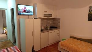 a kitchen with a refrigerator and a tv on the wall at Apartmani Lucky in Vrnjačka Banja