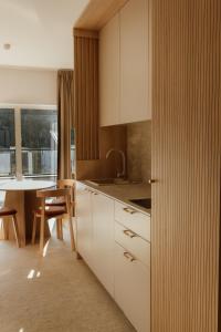 a kitchen with white cabinets and a table with chairs at Sea Shell Apartments Łukęcin in Łukęcin