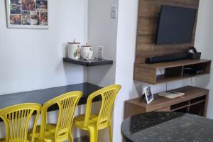 una sala da pranzo con sedie gialle, un tavolo e una televisione di Lençóis Park Residence Flat 106 Caburé a Barreirinhas