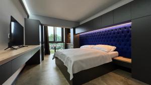 a bedroom with a large bed with a blue headboard at Spill Apartments in Kaluža