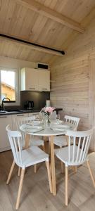 a dining room with a table and white chairs at Szalona Gęś in Gąski
