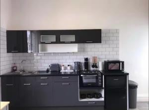 a kitchen with black appliances and a white wall at 55 Studio 4 Uplands in Swansea