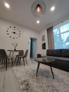 a living room with a couch and a clock on the wall at UrbanHome Rokiškis in Rokiškis