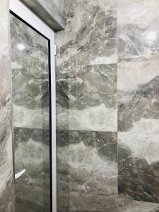 a glass shower door with a stone wall at Apartments panoramic Ana in Sarandë +75 photos