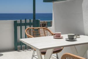 a white table with two cups and chairs on a balcony at Panorama in Myrtos