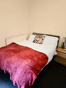 Un dormitorio con una cama con una manta roja. en Valla Haven Serviced Private Room in Northampton Centre with WiFi, en Northampton