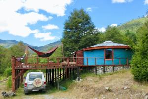 a house with a hammock and a car parked in front at Aguas Sagradas de Panqui in Curarrehue