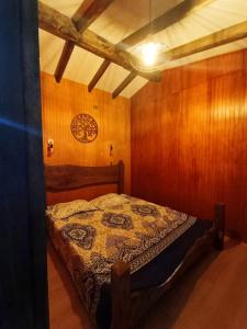 a bedroom with a bed in a room with wooden walls at Aguas Sagradas de Panqui in Curarrehue
