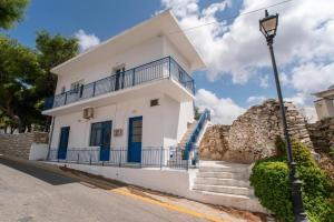 a white house with blue doors and stairs at kefos apartments paros in Kóstos