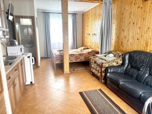 a living room with a leather couch and a kitchen at Гармонія in Skhidnitsa