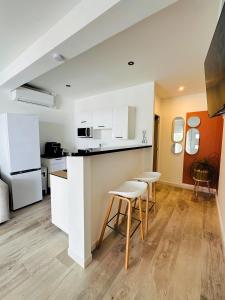 a kitchen with white cabinets and stools in a room at La villa Luna Rossa in Chambort +4 photos