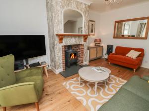 a living room with a fireplace and a tv at Rose Briar Cottage in Morpeth