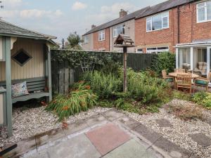 a garden with a bench and a fence at Rose Briar Cottage in Morpeth