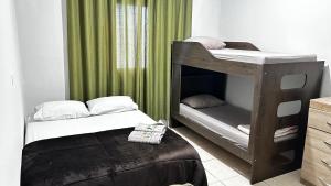 two bunk beds in a room with green curtains at 10 MIN AEROPORTO GUARULHOS in Guarulhos