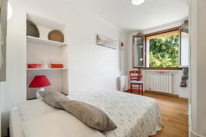une chambre blanche avec un lit et une fenêtre dans l'établissement La Maison de Noélie - RDJ, à Le Bar-sur-Loup