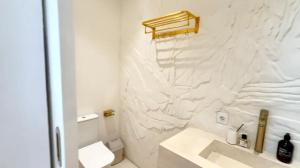 Un baño blanco con lavabo e inodoro. en Bali Ocean Uluwatu Retreat 2Fls Gold, en Uluwatu