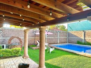 a backyard with a swimming pool under a wooden pergola at Bonita Quinta Familiar in Itzamatitlán