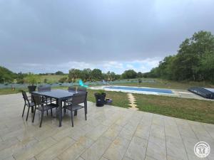 un patio avec une table et des chaises à côté d'une piscine dans l'établissement La Maison de L'Espagnol - FR-1-616-496, à Bayac