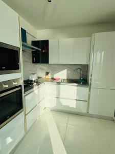 Il-Gżira taʼ Forti ManoelにあるPanoramic & Jacuzzi Seafront, Seaview Sliema Penthouseの白いキッチン(白いキャビネット、電化製品付)