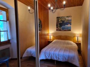 a bedroom with a bed and a mirror at Charmante Maison de Village 2 Chambres, Proche Télécabine et Centre, Tout Confort - FR-1-642-13 in Morillon