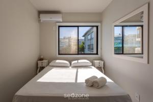 ein Schlafzimmer mit zwei Betten und zwei Fenstern in der Unterkunft Condomínio bem localizado a 100m da Praia - CSC in Florianópolis + 61 Fotos