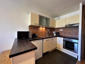 a kitchen with white cabinets and a black counter top at Appartement confort pour 5 aux Menuires - Animaux admis - FR-1-452-41 in Les Menuires +12 photos
