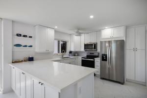 une cuisine avec des armoires blanches et un réfrigérateur en acier inoxydable dans l'établissement Gorgeous Island Beach Club Condo BRAND NEW, à Sanibel
