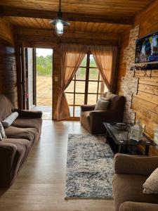 a living room with two couches and a tv at Cabaña Luz de Luna en La Esmeralda Rocha in La Esmeralda 