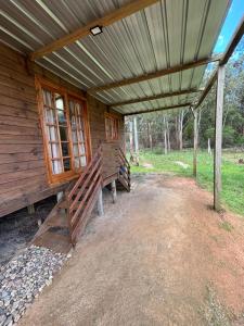 a wooden cabin with two benches under a roof at Cabaña Luz de Luna en La Esmeralda Rocha in La Esmeralda 