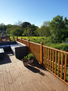 a wooden deck with furniture and plants on it at Trevella Lakeview Lodge in Newquay