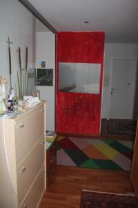 a room with a red wall and a dresser at Beautiful 14 m2 room in Wünnewil