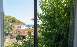 a window with a view of a house and the ocean at Casa Vella de Casa Torrent in Canet de Mar