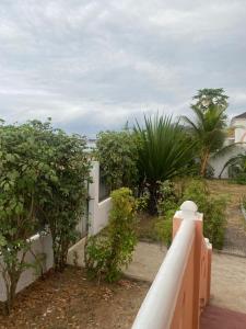 una valla blanca con árboles y plantas en un patio en CASA da Baía by NaturAlegre, en São Tomé