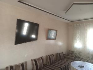 a living room with a couch and a tv on the wall at Appartement avec piscine pré Aereport et stade in Tangier