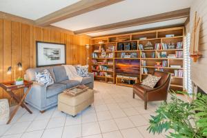 ein Wohnzimmer mit einem Sofa, einem Stuhl und Bücherregalen in der Unterkunft Keys Retreat by Paradise Retreats in Ventura