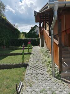 a stone walkway next to a house with a porch at LiLu Apartman in Felsőtárkány