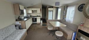 a kitchen and living room with a couch and a table at Poppy Caravan in Leysdown-on-Sea