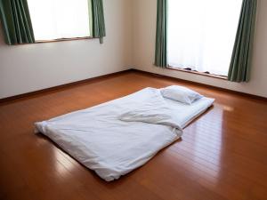 a white bed on the floor in a room with two windows at Genki na yado Asahi - Vacation STAY 62934v in Asahi