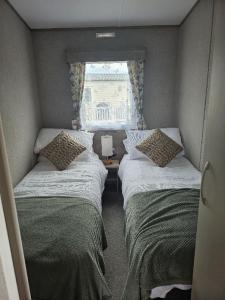 two beds in a small room with a window at Stunning 6 Berth Caravan Near To The Beach At Pakefield Ref 68115Cr in Lowestoft +8 photos