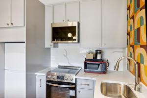 リバーヘッドにあるGreenview Inn Riverheadの白いキャビネットとシンクと電子レンジを備えたキッチン