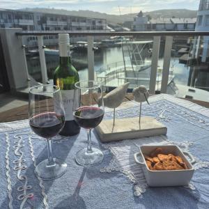 a table with two glasses of wine and a bowl of food at South Quay no 6 in Knysna