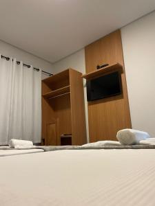 Schlafzimmer mit einem Bett, einem TV und einem Schrank in der Unterkunft Pousada Ebenézer de Cordeiro rj in Cordeiro