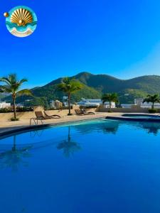 a large swimming pool with chairs and a beach at Mar y Sol-El peñón del rodadero in Santa Marta