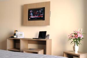 a room with a bed with a tv on a wall at The Originals City, Hôtel de France, Bessines-sur-Gartempe (Inter-Hotel) in Bessines-sur-Gartempe