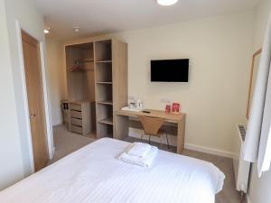 a bedroom with a bed and a desk and a television at The Orchard Outlook at Eamont Park in Penrith +10 photos