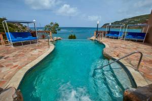 a swimming pool with chairs and the ocean in the background at Divi Little Bay Beach Resort in Philipsburg +112 photos